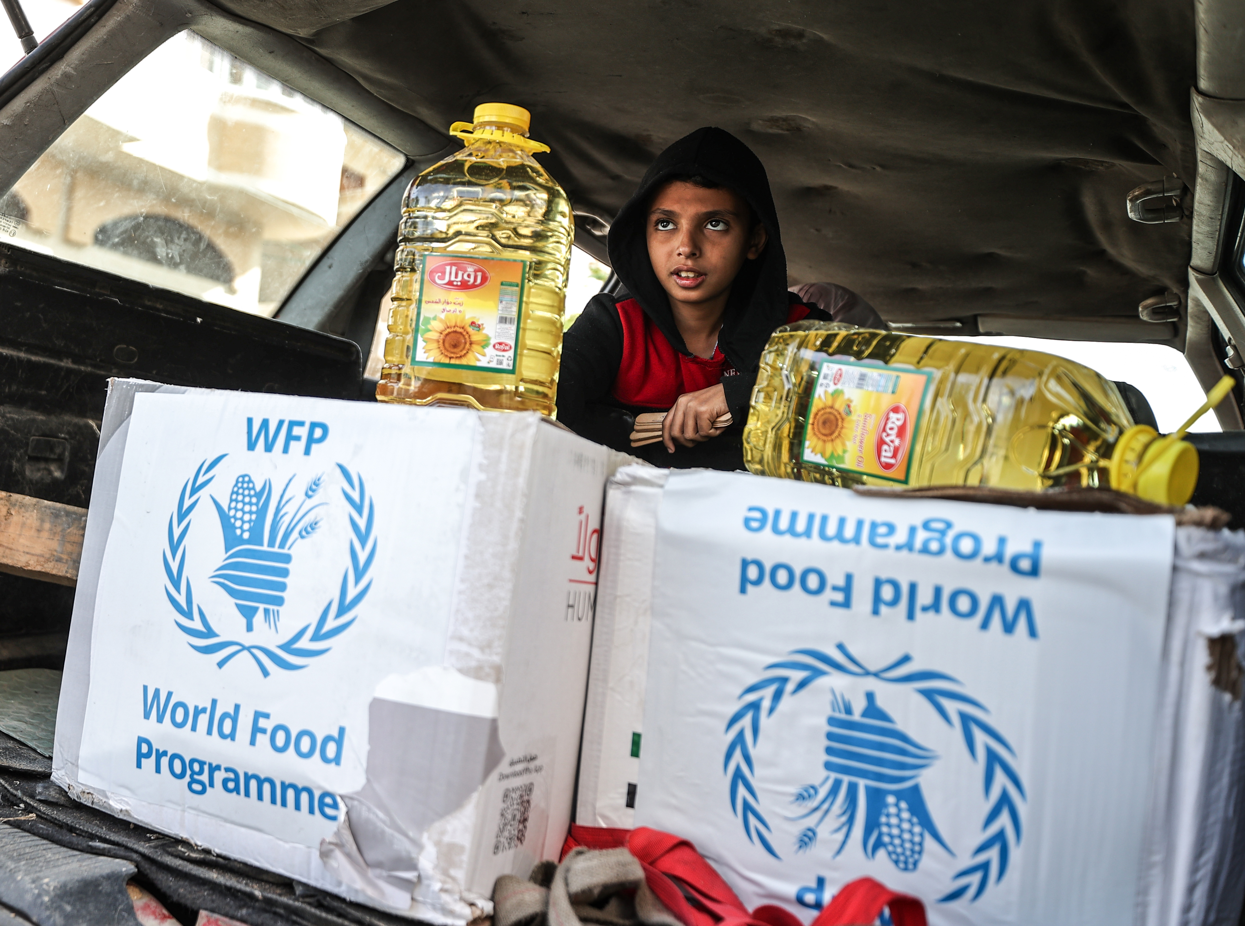 Niño se inclina sobre unas cajas con raciones de alimentos distribuidas por el Programa Mundial de Alimentos. 