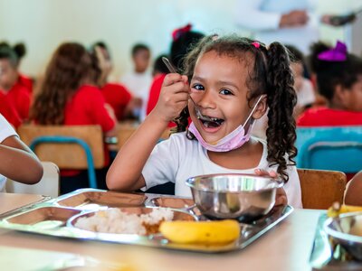 Niña comiendo una comida caliente en su escuela