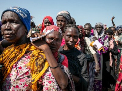 Mujeres esperan en fila bajo el sol para recibir asistencia