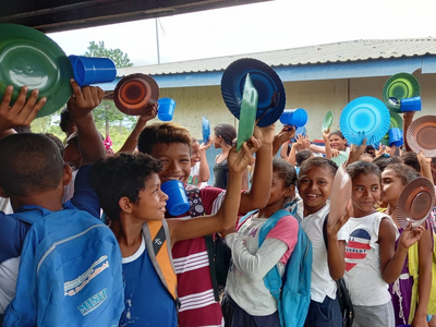 Un grupo de niños se prepara para recibir su almuerzo escolar.