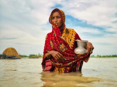 Una mujer camina con el agua a la cintura en una zona inundada