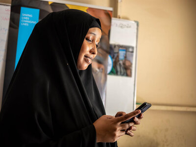 Hani Mohamed (24) utiliza su teléfono móvil para pedir comida a través de una tienda online en un centro de distribución de alimentos del WFP situado en la zona K4 de Mogadiscio.