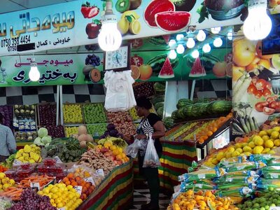 Una mujer compra frutas y verduras frescas en un mercado.