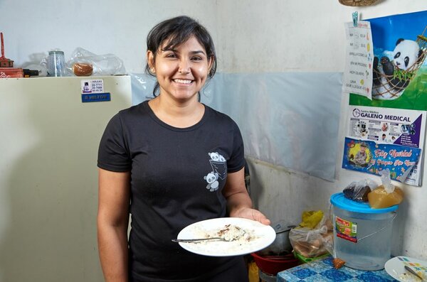 Keyla del Valle, migrante venezolana, con un plato de comida en su cocina.