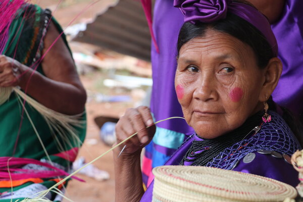Una mujer guaraní teje sus artesanías de hoja de palma.