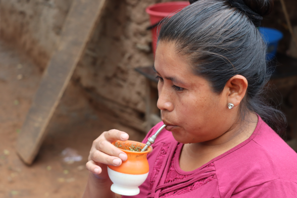 Una mujer guaraní toma yerba mate en su guampa y con una bombilla.