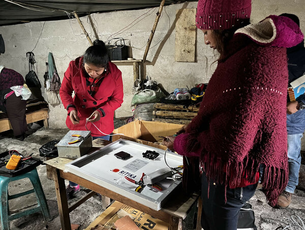 Dos mujeres trabajan dentro de una casa instalando la electricidad.