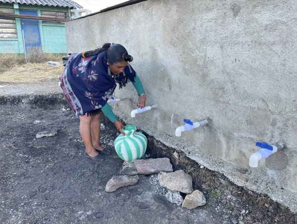 Una mujer llena de agua un cántaro en Guatemala.