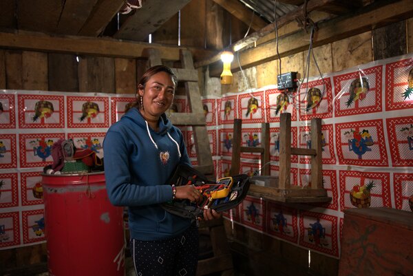 Carolina Galicia instala luz dentro de una vivienda. En sus manos muestra sus herramientas de trabajo.