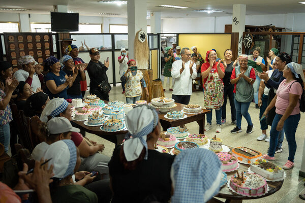 Un grupo de mujeres celebra el final de su curso de reposteria. Las mujeres pusieron sus tortas sobre una mesa.