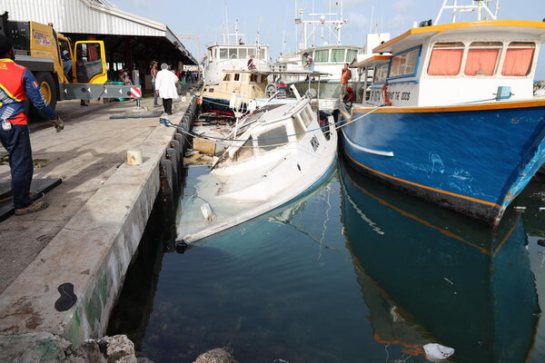 El barco de un pescador yace hundido en el atracadero del puerto de Bridgetown, Barbados, debido a los oleajes del huracán Beryl.