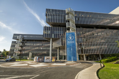 World Food Programme headquarters in Rome, Italy, featuring the modern office complex and WFP banner at the main entrance under a clear blue sky.