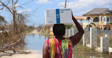 Una mujer regresa a su casa llevando una caja de alimentos de emergencia del WFP sobre la cabeza, tras una distribución realizada en apoyo a la respuesta de emergencia del Gobierno de Jamaica en la zona de Arlington, en la parroquia de St. Elizabeth, una de las más afectadas por el huracán Melissa.