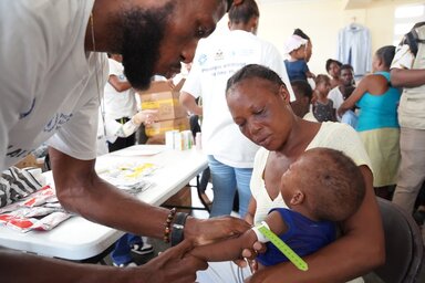  Un trabajador de WFP realiza la medición de la circunferencia media del brazo (MUAC) de un bebé en una clínica móvil de nutrición en la Escuela Joseph Claude Bernard