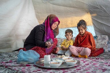 Una madre y sus hijos comen sus alimentos dentro de una tienda.