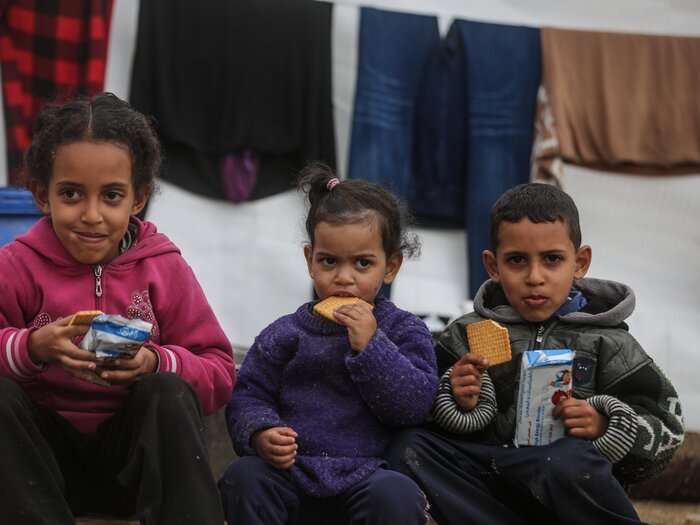 Tres niños comen dátiles proporcionados por WFP.