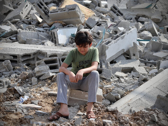 Un niño aparece sentado en medio de los escombros de un edificio en la ciudad de Gaza que fue destruido por un proyectil.