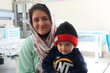 A smiling mother, with a patterned veil, and child wearing a ski cap at a health clinic in Afghanistan. Photo: WFP/Ziauddin Safi