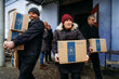 People carry WFP food boxes from a warehouse, distributing essential supplies to support families in need during cold weather.