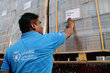 A WFP UN Humanitarian Response Hub employee pastes a Benghazi, Libya destination on a shipment of humanitarian supplies. Photo: WFP/Peppino Circa