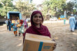 Copilot said:  Person holds a box of fortified biscuits during an aid distribution, while people collect relief supplies from a truck in the background.