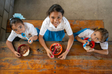 Dana (center), Ashly Nayeli (left) and Anyeli Sofia (right) sit together to eat the hot school meal: red bean soup.