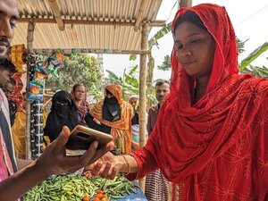 Una mujer en el mercado compra sus vegetales a través de un código QR.