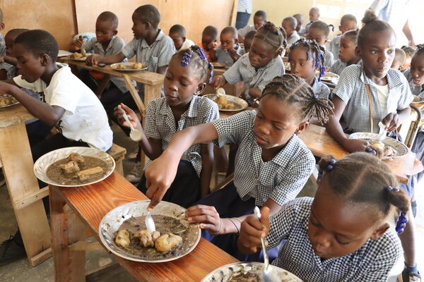 Estudiantes de primaria almuerzan en los pupitres de sus aulas en la escuela de la aldea de Belle Onde, en una zona árida y empobrecida del centro de Haití. Foto: WFP/Alexis Masciarelli