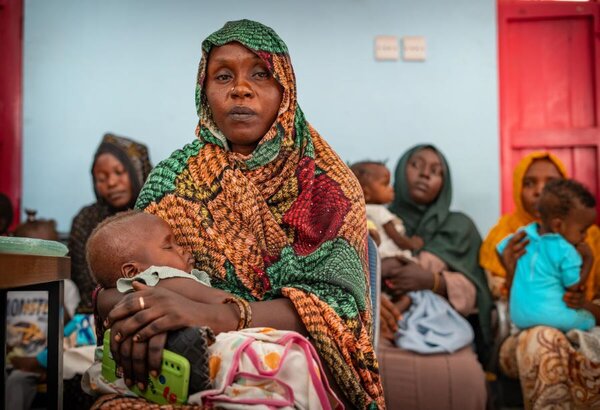 Foto: WFP/Abubakar Garelnabei, Una niña duerme en las manos de su madre mientras espera su turno para tomar las medidas en el centro de salud apoyado por WFP en Port Sudan.