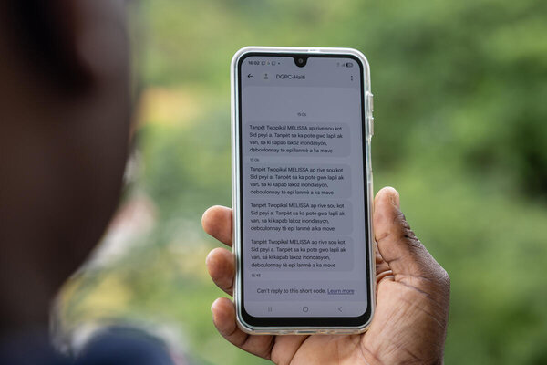 Haiti. As Tropical Storm Melissa approaches the Haitian coast, early warnings are sent out by the General Direction of Civil Protection via text message. En Haití, una persona lee un mensaje de texto advirtiendo sobre la llegada de una tormenta tropical.