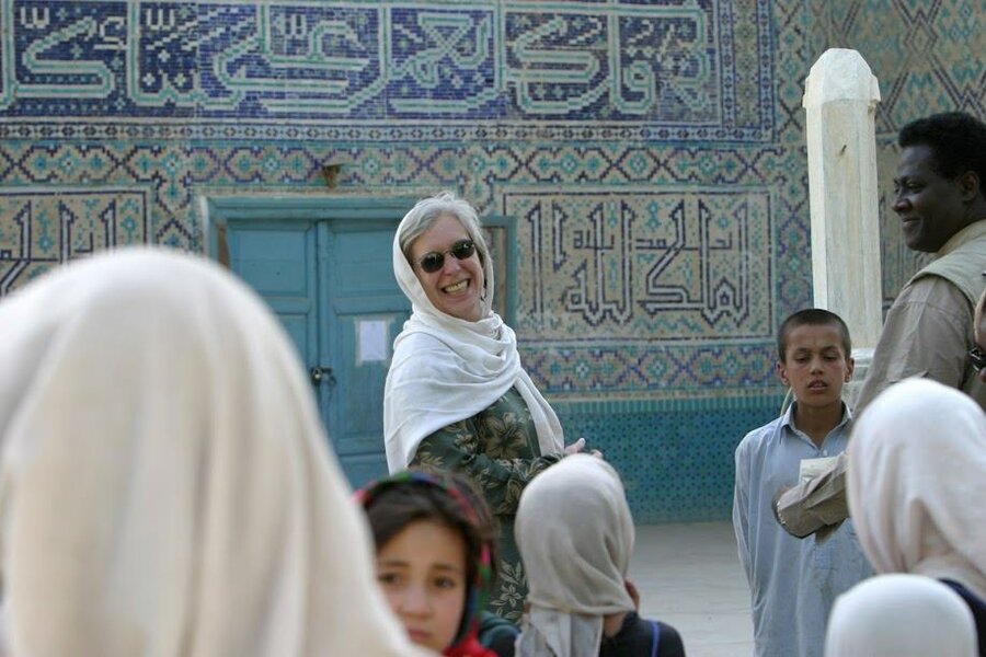 woman in white headscarf smiling on background of mosque mosaics