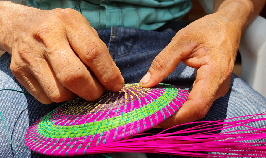 Las manos de Santiago Camacho tejen una artesanía guaraní