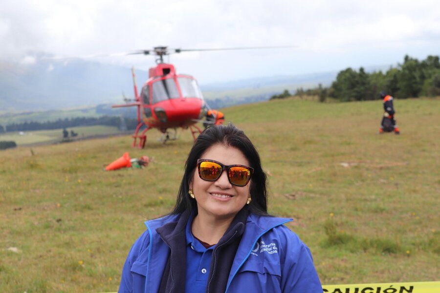 Una funcionaria del WFP mira a la cámara. Al fondo se ve un helicóptero rojo que ha aterrizado.