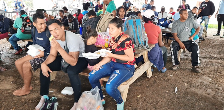 Varios migrantes sentados comiendo