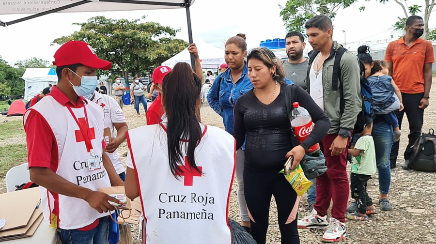 Trabajadores de la Cruz Roja Panameña distribuyen recursos a una fila de migrantes