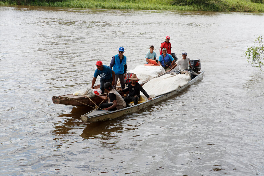 Dos chalupas (cayucos o botes) cargados de comida navegan por un rio