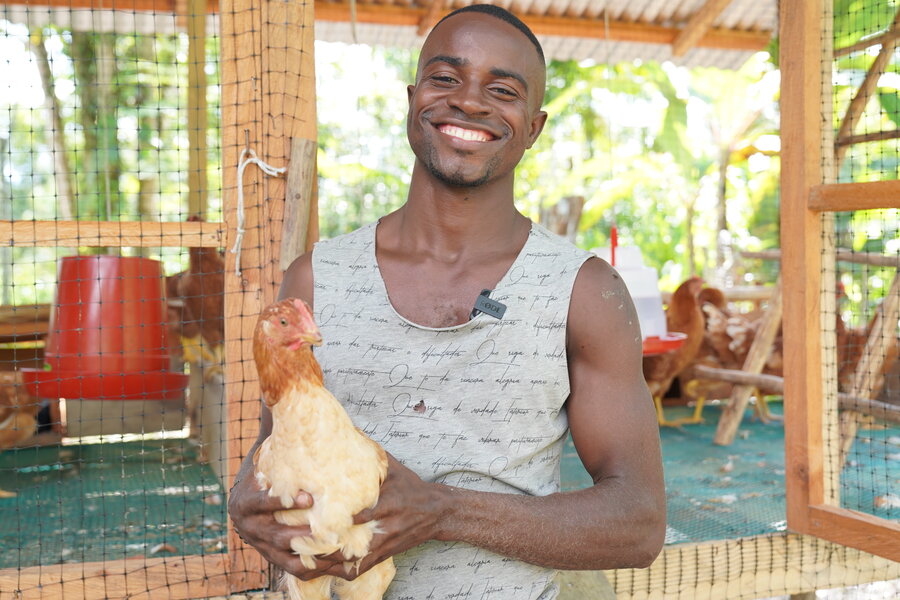 Ramiro Mena sonríe mientras sostiene una gallina.