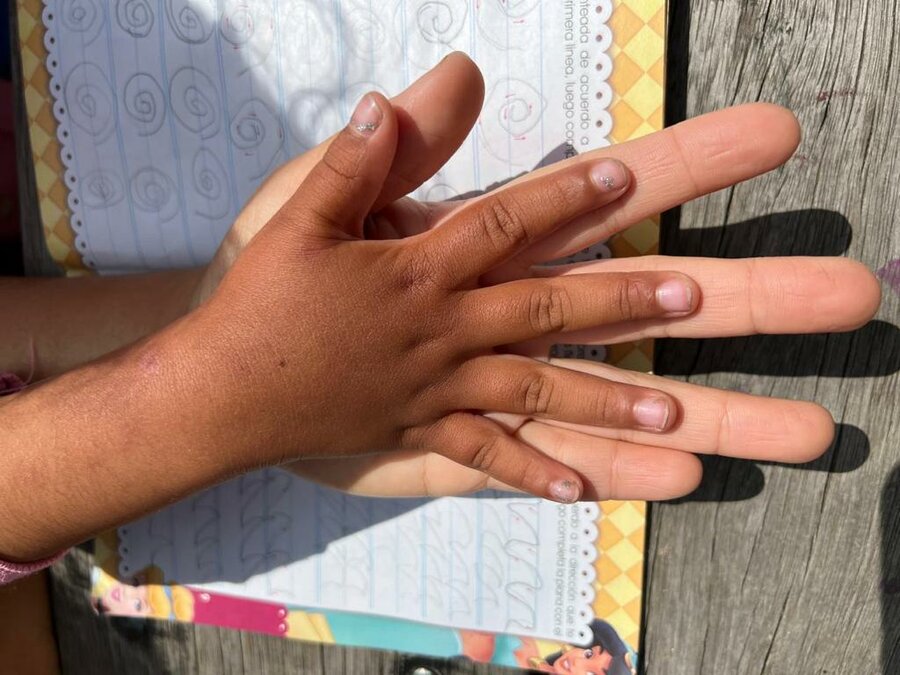 Foto de la mano de un niño o niña sobre la mano abierta de su madre.