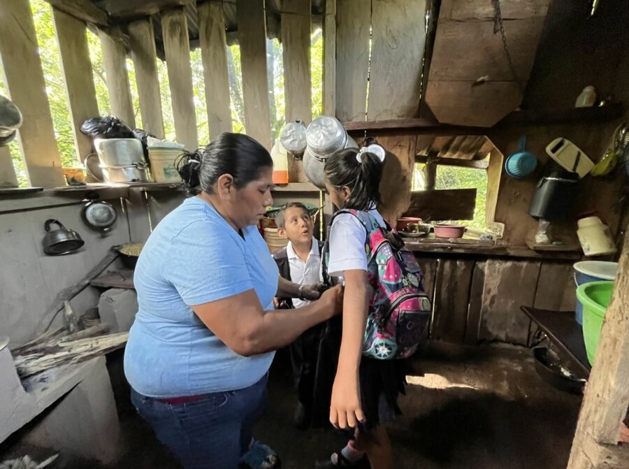 Una mujer arregla a sus hijos para ir a la escuela en la cocina de su casa.