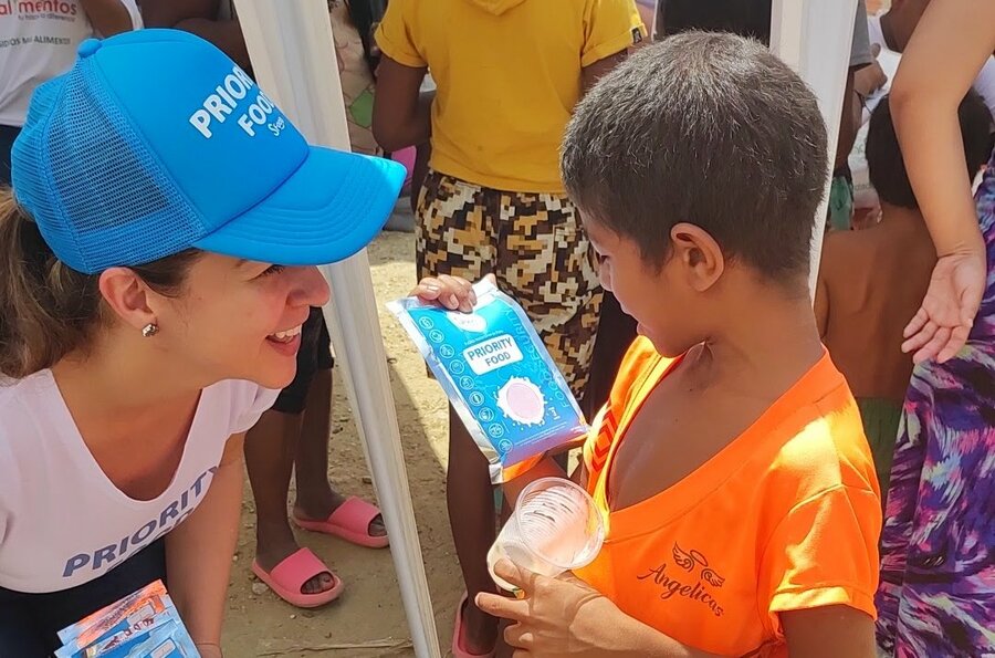 Una colaboradora de Global Meals entrega una ración a un niño.