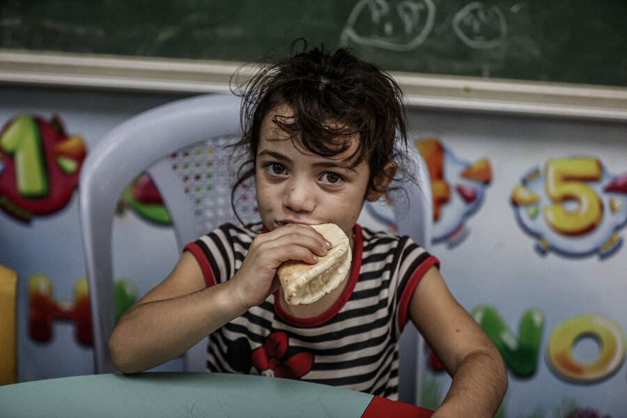 Girl sat at table eating bread