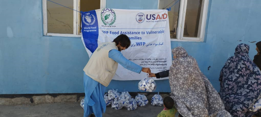 WFP staff member distributes food parcels to women in burqas in Afghanistan
