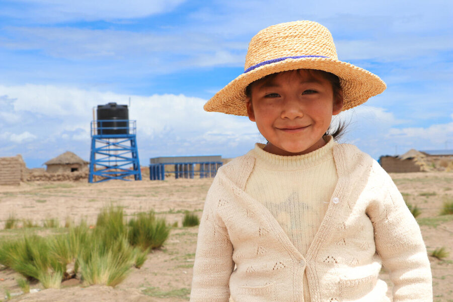 Una niña uru lleva puesto su sombrero tradicional. Ella está frente a una granja de piscicultura en el altiplano boliviano.