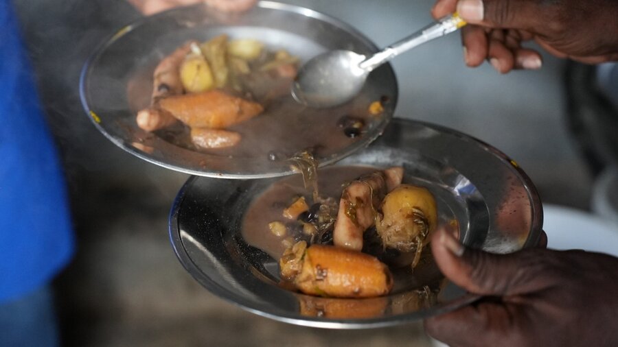 close-up of hands serving vegetable soup in Haiti