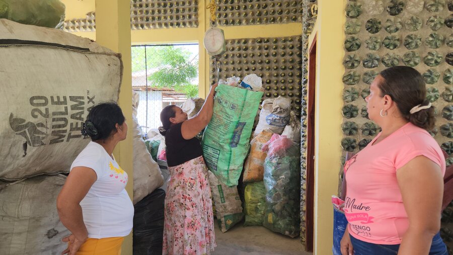 Tres mujeres pesan el material que van a reciclar. 