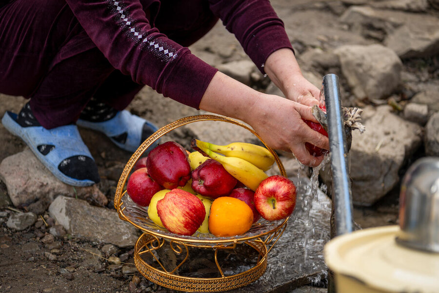 Person crouching down over a basket of fruit