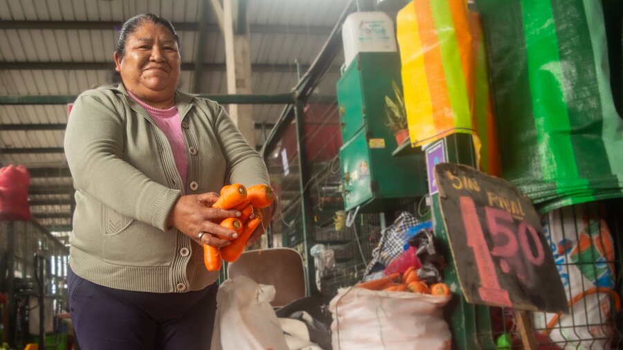 Rosario sostiene zanahorias en sus manos en un mercado de Perú. Foto: WFP / Malena Melgar