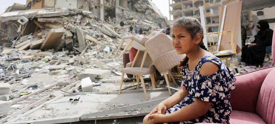 Una niña sentada entre los escombros de edificios destruidos en Gaza. Foto: © UNRWA 