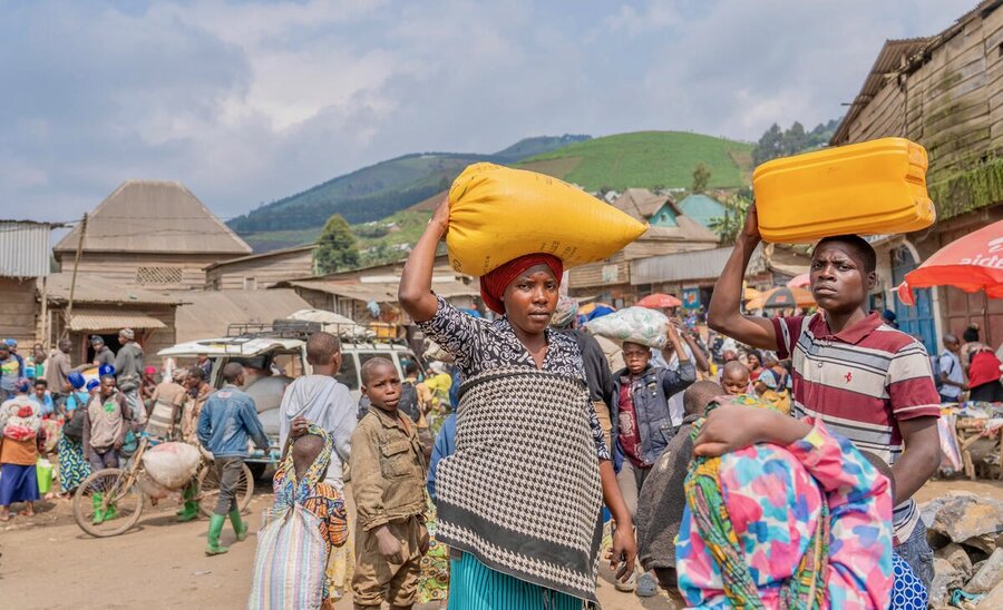 People in eastern DRC carry food sacks and balance plastic containers on their head. Photo: WFP/Benjamin Anguandia
