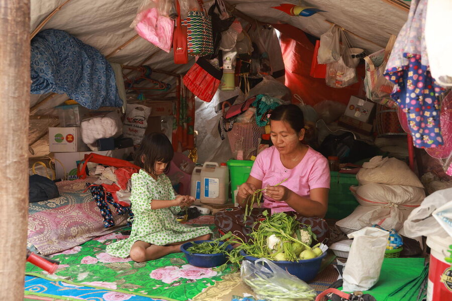 A woman and a little girl sit in a cloth tent sorting through greens and other food. Photo: WFP/Htet Oo Linn